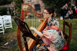 Sam MacAdam plays the harp in a garden setting