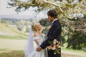 a bride and groom looking at one another in a garden setting under a tree