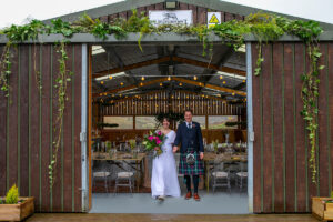 A couple stands at the entrance to the barn at Blackhouse Forest Etate