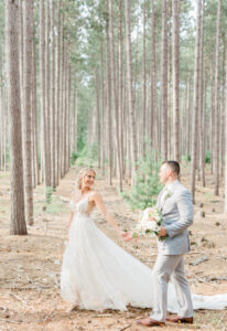 Bride and groom on their own embracing in forest train dress gown holding hands walking