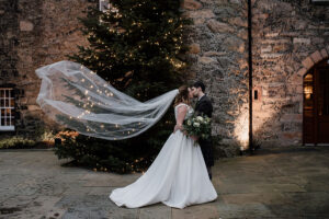 a bride and groom kissing in front of a Christmas tree at Meldrum House