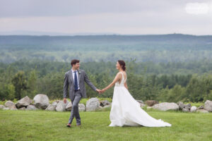 Bride and groom walk along scenic ridge at Fruitlands Museum wedding in Harvard, MA.