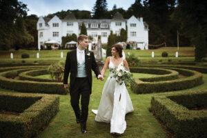a bride and groom walking hand in hand outside Achnagairn Castle