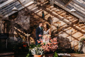 a bride and groom in a greenhouse at Cambo Estate