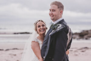 a smiling bride and groom on the beach at West Kilbride