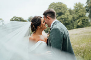 bride and groom kissing with veil in foreground