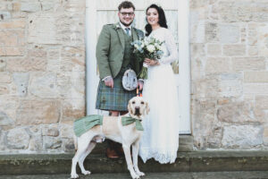 a bride and groom with their Labrador wearing a kilt