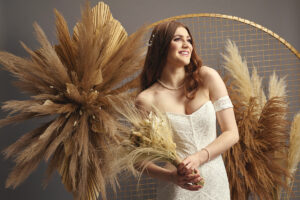 Model standing next to gold mesh moongate wedding arch wearing wedding Watters wedding dress from Innate Bridals