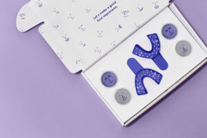 An open box from Smile Direct Club on a purple backdrop