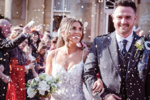 a bride and groom walking through confetti outside Balbirnie House
